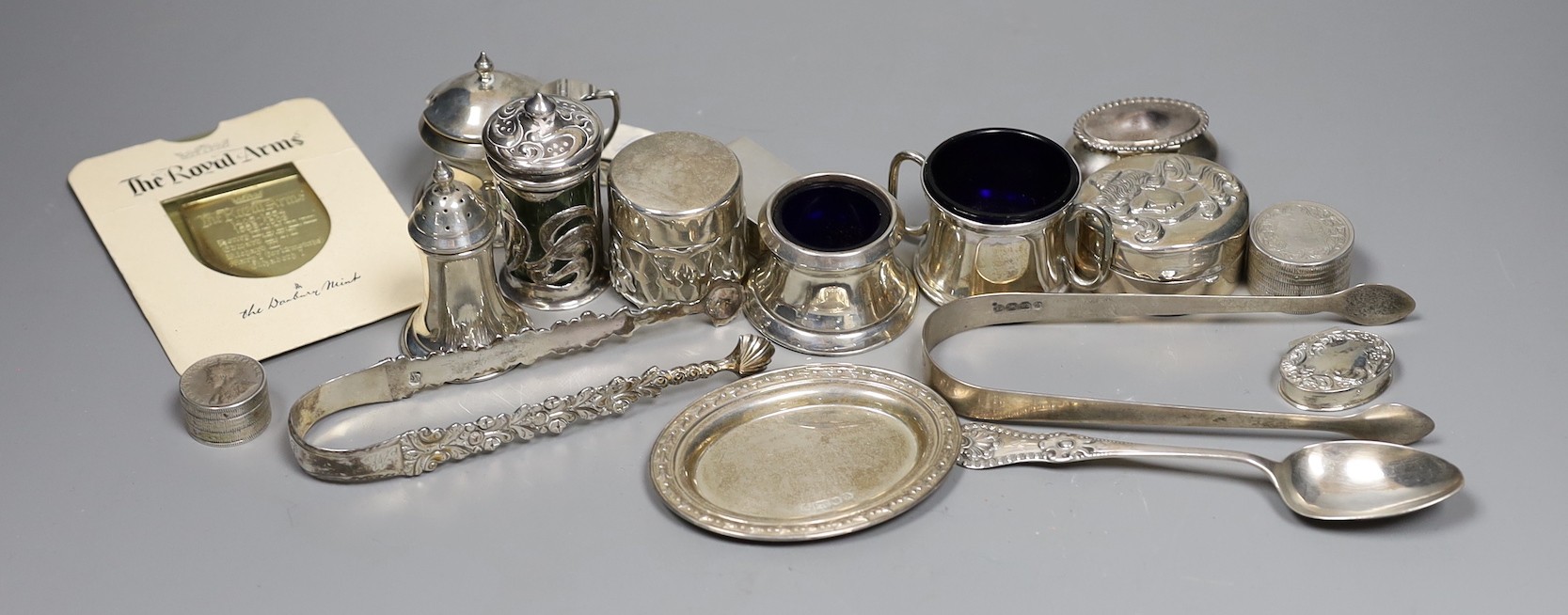 A small group of collectable small silver and white metal items including two pairs of 19th century sugar tongs(one a.f.), later condiments, match sleeve, dish pill box, etc.